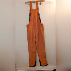 Zermatt insulated snow bibs in a bold orange color.